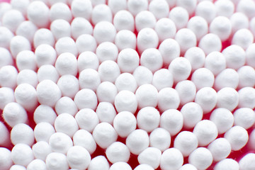 Closeup view from above on round pack of cotton buds on pink background