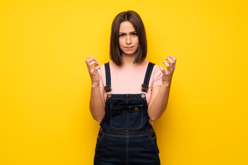 Young woman over yellow wall frustrated by a bad situation