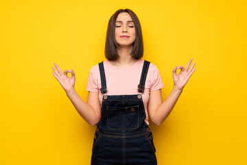 Young woman over yellow wall in zen pose