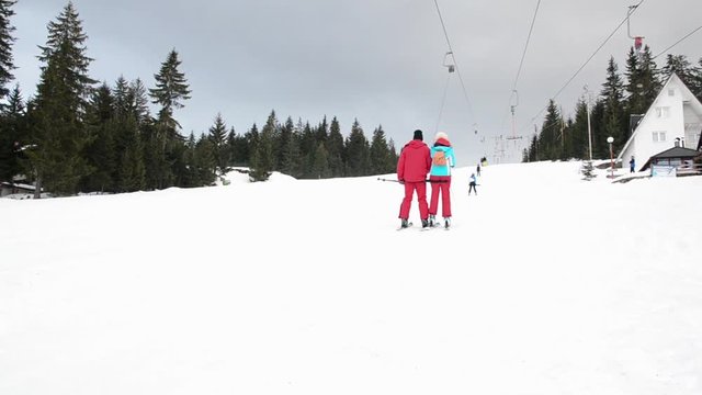 Skiers using ski lift anchor on the mountain. People moving slowly uphill on drag lift on snow covered landscape. Winter sports, skiing, recreation and holidays concept. 