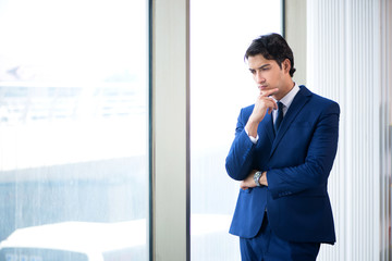 Young handsome businessman standing at the window 
