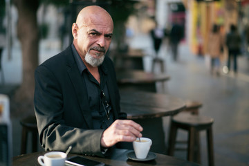 Senior man drinking coffee in bar terrace