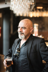 Senior man in bar drinking beer in indoor image