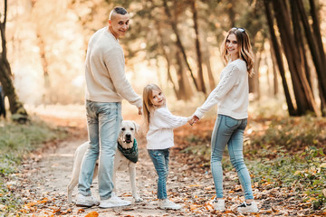 Fototapeta premium Happy beautiful family with dog labrador is having fun together walking the in park.