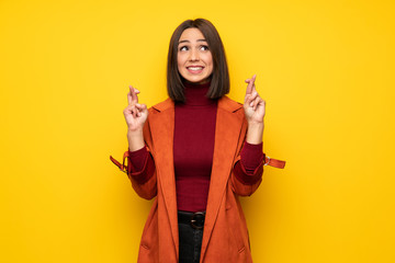 Young woman with coat with fingers crossing and wishing the best