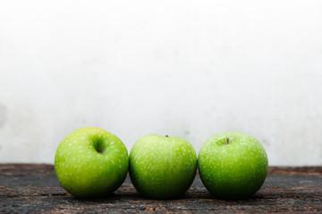 Three fresh green apples placed on the wood