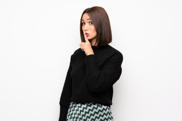 Young woman over white wall showing a sign of silence gesture putting finger in mouth