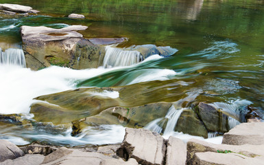 stones and mountain river with small waterfall, blurred background