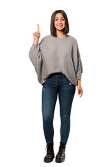 A full-length shot of a Young woman showing and lifting a finger in sign of the best over isolated...