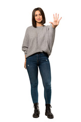 A full-length shot of a Young woman counting five with fingers over isolated white background