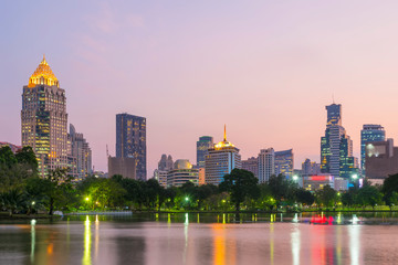 Fototapeta na wymiar View of lake in Lumpini park with high building of business center district of Bangkok in background at sunset. Travel to Thailand.