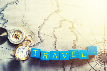 Travel background concept. “Travel “ wording on wooden cube with golden compass and pocket watch on old map.