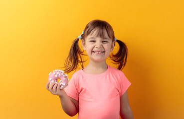 Four-year-old girl in a pink t-shirt eat donut.