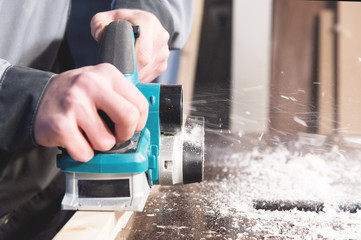 The hands of a carpenter working woodworking power tools. Close up of the work of the electric...