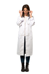 A full-length shot of a Young doctor woman with glasses and surprised over isolated white background