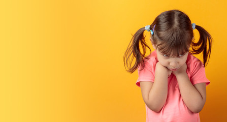 Offended girl in a pink t-shirt on an orange background.