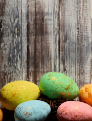 Happy Easter. Bright colored painted eggs on the bottom on a brown wooden surface. Cropped shot, background, vertical, top view, free space. Concept of religion and tradition.