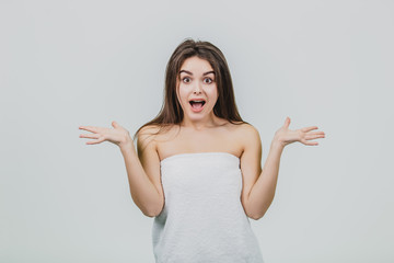 Fototapeta premium Beautiful young girl with smooth skin on a light background with natural make-up and curly dark hair.