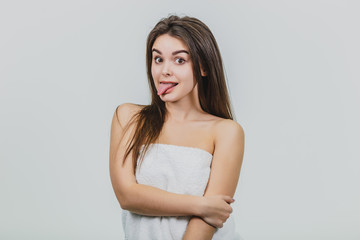 Fototapeta premium Beautiful young girl with smooth skin on a light background with natural make-up and curly dark hair.