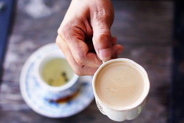Hot coffee in a ceramic cup, hold in a hand of asian man skin, 