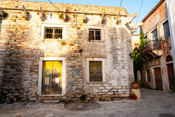 Fototapeta na wymiar An old house and an alley bathed in sunlight in Greece