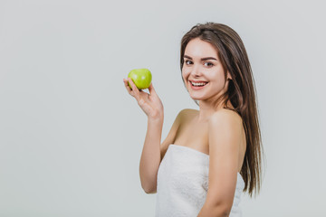 Portrait of an attractive Caucasian girl smiles. Woman isolated on white background. Holds the green apple in hand. Good clean skin.