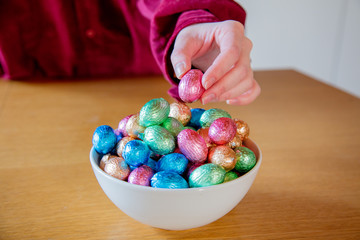 female hands try to take Easter eggs in plate