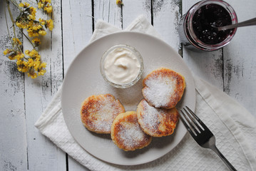 Cheese cakes with sour cream and jam in a plate on the table.