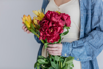 Female hands holding bouquet of peonies and  Leucadendron
