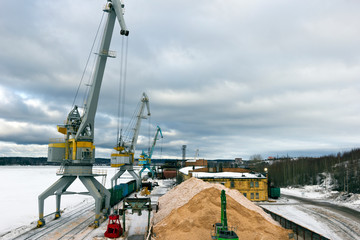 Obraz premium cargo port in winter. Unloading of wood chips from railway cars
