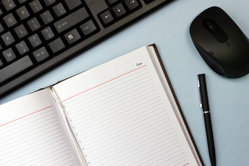 Modern journalism tools, keyboard, mouse, diary and a pen on a blue table. work of a journalist at a personal computer