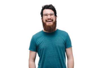 Obraz premium Close up smiling young bearded man wearing eyeglasses, looking at the camera against white wall background