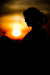 Silhouette of girl's face holding cloverleaf during sunset - Black and orange colors