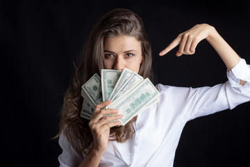 Successful beautiful business  young woman holding money US dollar bills in hand isolated on black background , business finance concept