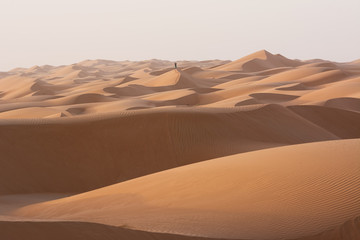 Fototapeta na wymiar Alone man in the desert dunes of the Wahiba Sand Desert (Oman)