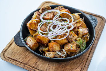 Fried potatoes with meat, broccoli and red onions decorated with rosemary in a frying pan on a wooden table top view