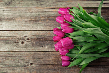 Bouquet of pink tulips on a wooden plank table. Toned photo.