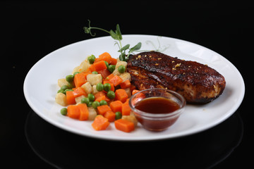 chicken fillet, baked with spices and covered with an appetizing crust, on a plate with vegetables and sauce