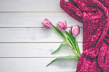 Flowers and sweater on table Top view of knitted sweater and pink tulips placed on white timber table. Save space