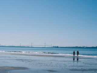 Fototapeta na wymiar People walking along the shore of the beach