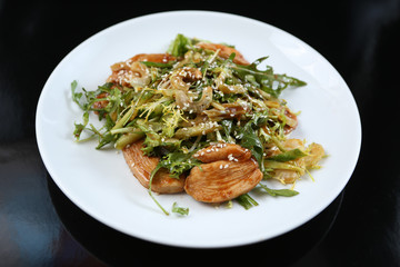 salad of a large amount of greens, green celery, arugula, boiled meat fillet with sauce and sesame