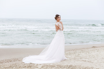 Fototapeta na wymiar young bride walks on the beach in cloudy weather