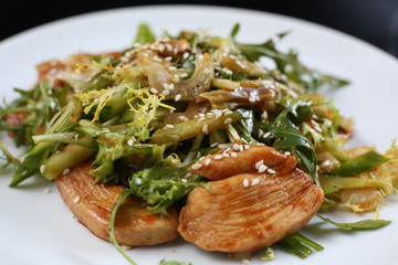 salad of a large amount of greens, green celery, arugula, boiled meat fillet with sauce and sesame