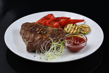 Beef kebabs on a plate with grilled vegetables, zucchini and Bulgarian red pepper, decorated with greens