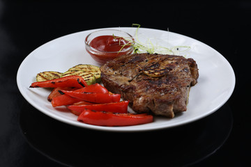 Beef kebabs on a plate with grilled vegetables, zucchini and Bulgarian red pepper, decorated with greens