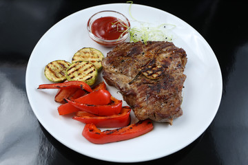 Beef kebabs on a plate with grilled vegetables, zucchini and Bulgarian red pepper, decorated with greens