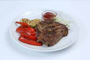 Beef kebabs on a plate with grilled vegetables, zucchini and Bulgarian red pepper, decorated with greens