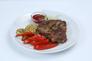 Beef kebabs on a plate with grilled vegetables, zucchini and Bulgarian red pepper, decorated with greens