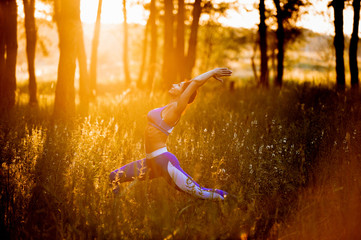 Fototapeta premium Young woman practicing yoga pose against a background of green nature in the forest