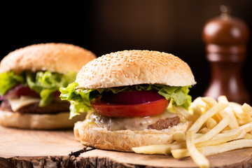 Tasty grilled beef burger with lettuce, cheese and onion served on cutting board with copyspace